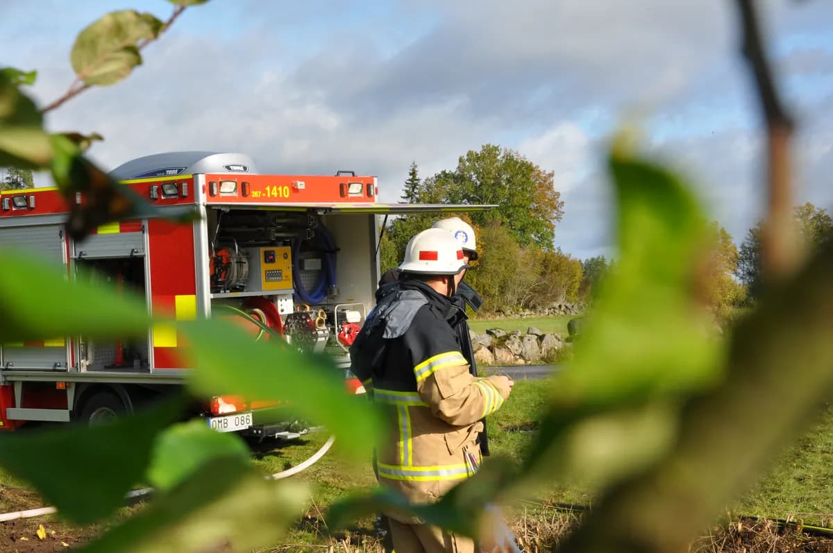 Firefighter at fire truck with open equipment compartments in rural setting