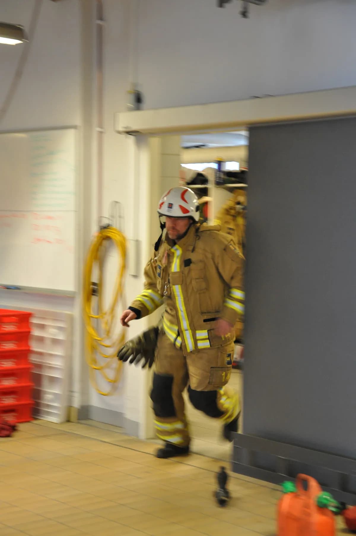 Firefighter in full protective gear running through doorway during emergency response